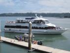 A small cruise ship pulling away from a dock. 